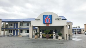 A motel with a large '6' sign, a covered entrance, and a parking lot.