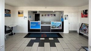 A reception area with a desk, a chair, a bulletin board, and a door.