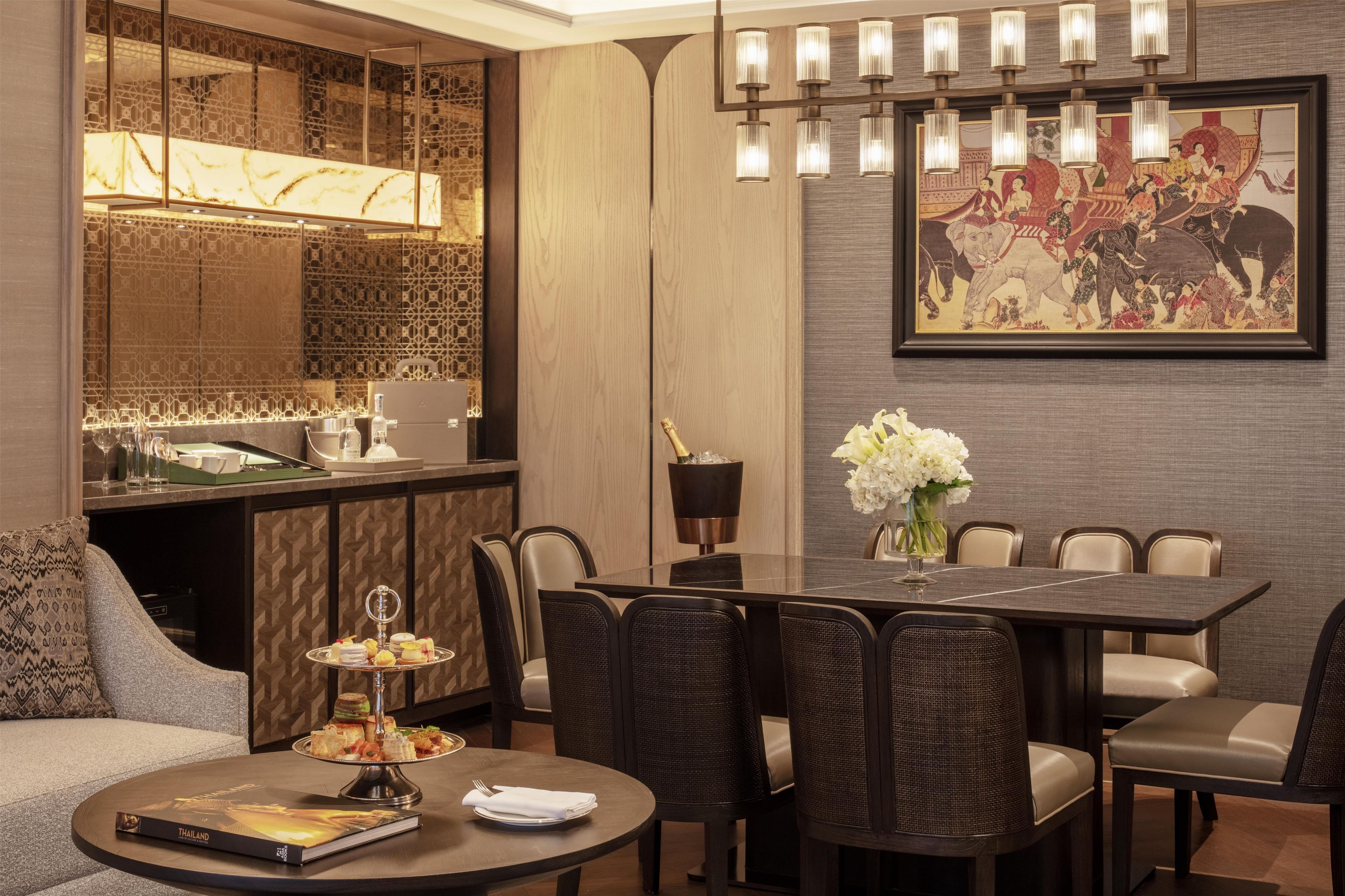 A modern dining area with a table set for six, a bar area with a minibar, and a large decorative painting on the wall.