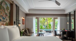 Ein Hotelzimmer mit Bett, einer Sitzecke mit Tisch, einem Schreibtisch und Blick auf Garten und Pool.
