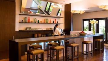 Une cuisine moderne avec des tabourets de bar en bois, un grand îlot central et une variété de vases colorés disposés sur des étagères.