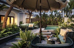 A lush outdoor area with seating, a pool, and tropical plants.