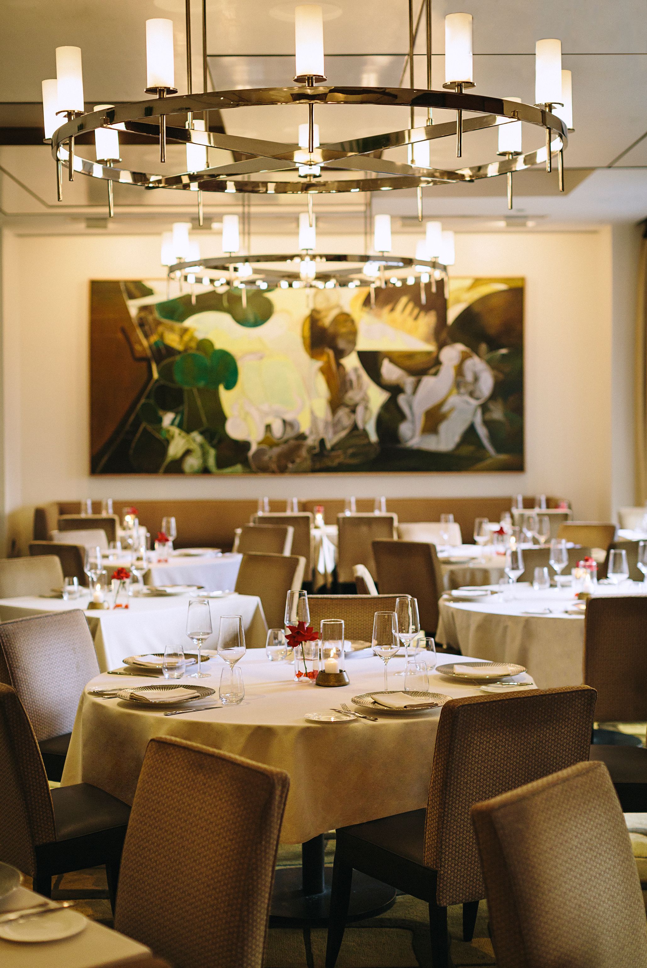A dining area with round tables, chairs, and a chandelier.