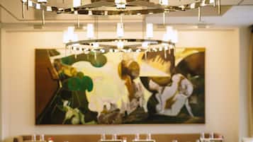 A dining area with round tables, chairs, and a chandelier.