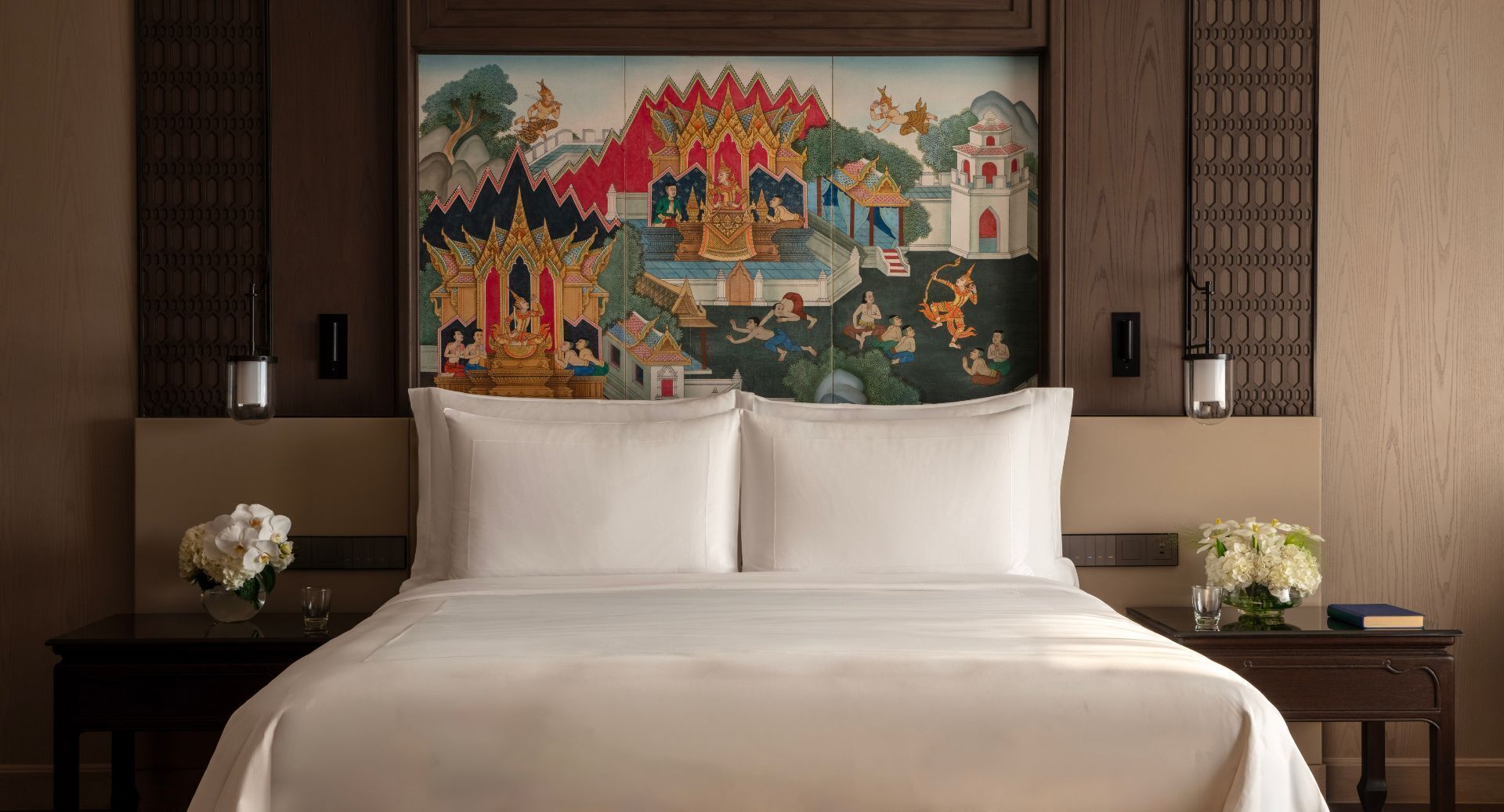 A hotel room with a large bed, two nightstands, a painting on the wall, and a night lamp on each nightstand.