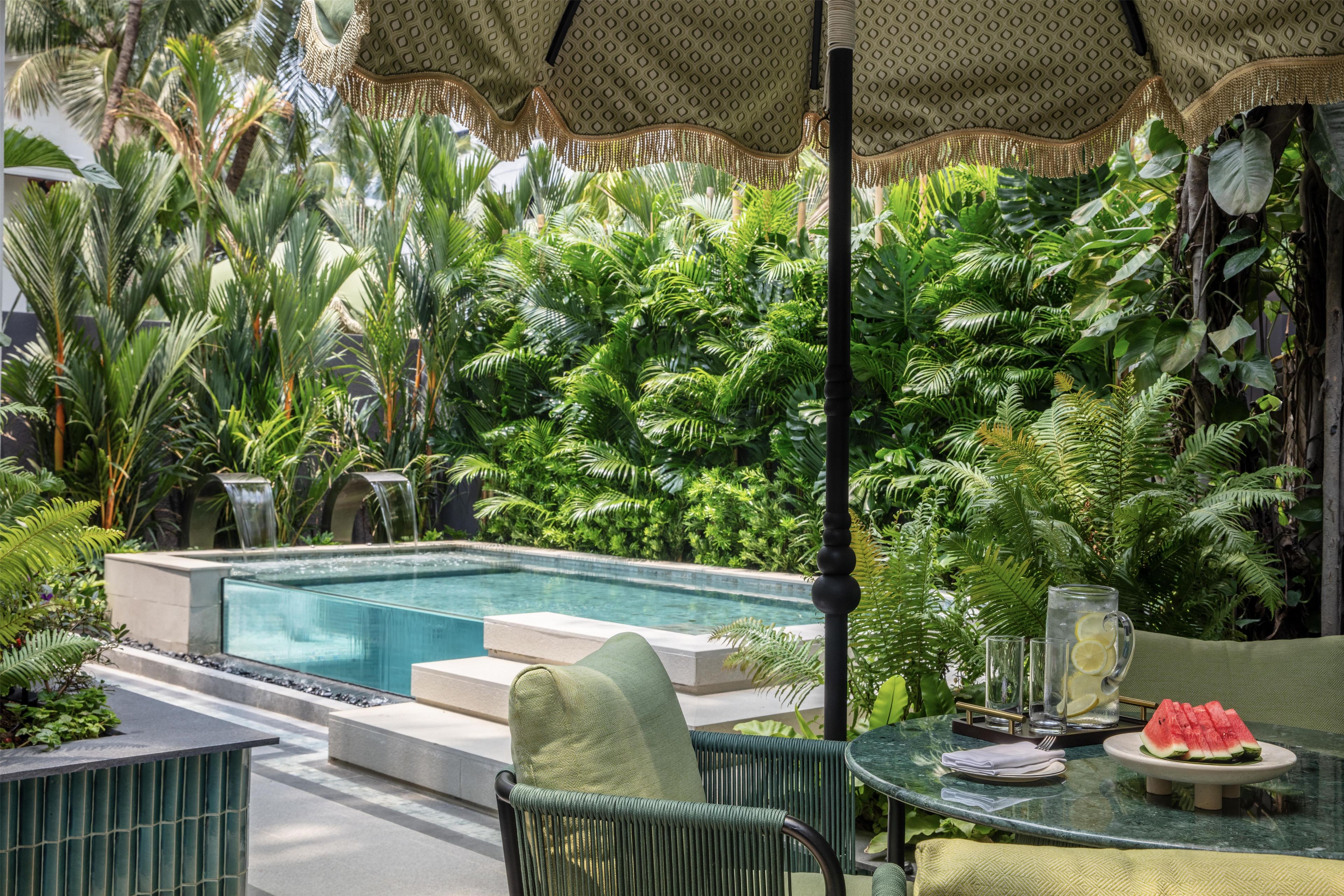 A pool area with a glass table, chairs, and a watermelon on the table.