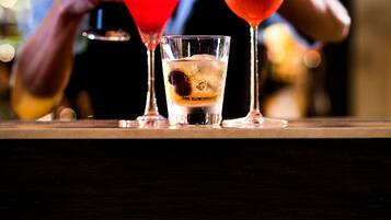 A bar with three cocktails, one with a flaming garnish.
