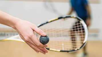 Una mano sosteniendo una pelota de tenis cerca de una raqueta.