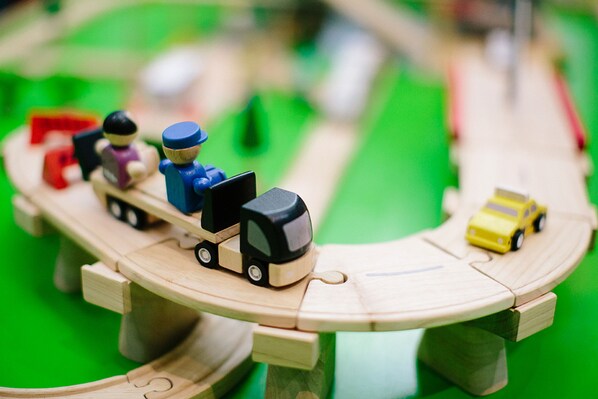 Un juego de tren de madera con una vía, un camión y un coche.