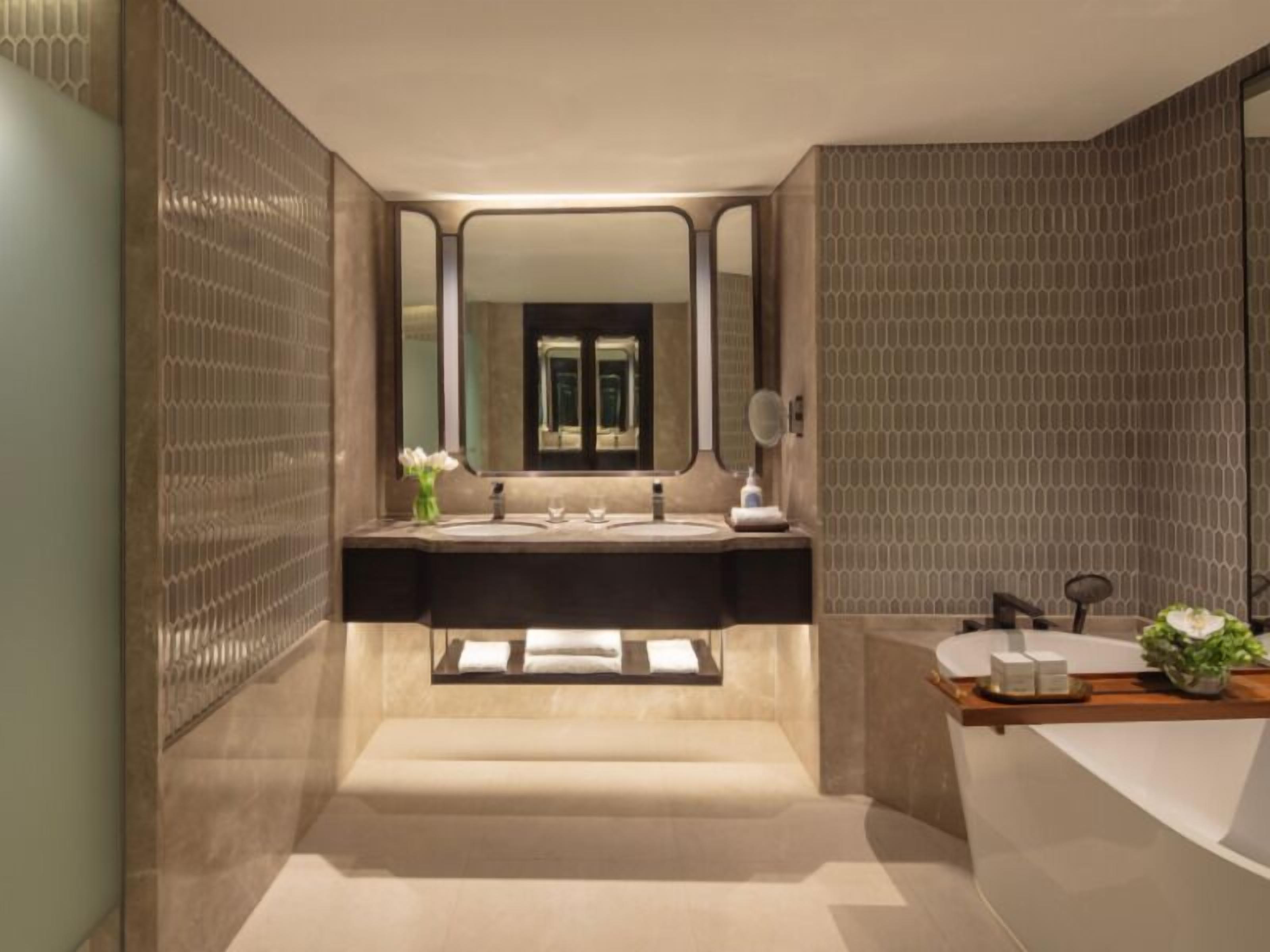 Une salle de bain moderne avec un meuble-lavabo à deux vasques, un grand miroir et une baignoire.