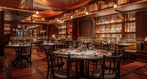 Un restaurant avec des tables rondes, des chaises et un sol en briques.