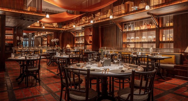 A restaurant with round tables, chairs, and a brick floor.