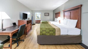 A hotel room with a wooden desk, a computer, a TV, two beds with headboards, a mirror, and a window. - Rodeway Inn St. Joseph (Saint Joseph)