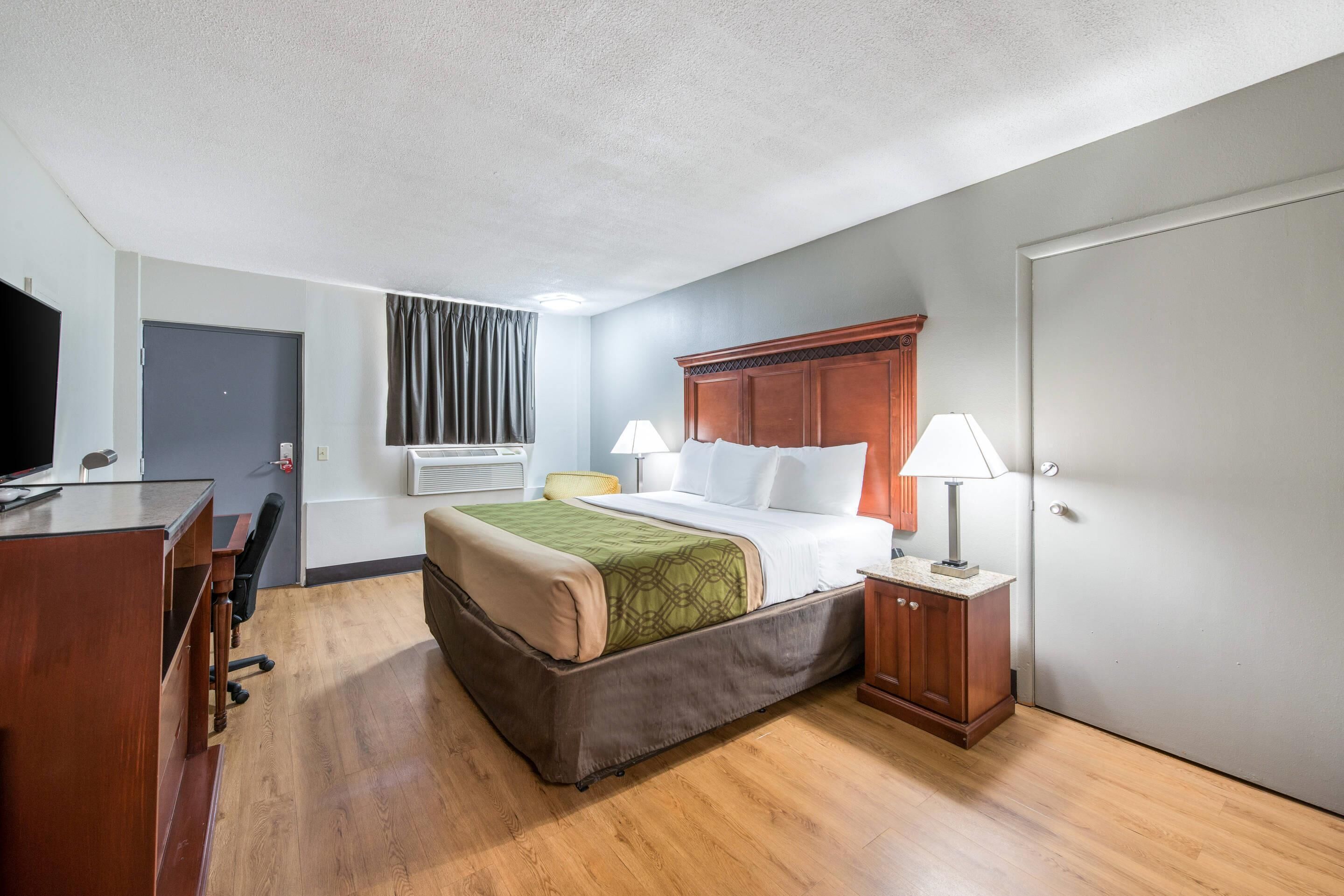 Habitación de hotel con cama, escritorio, silla y televisor.
