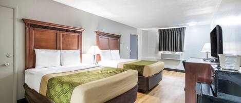 Habitación de hotel con dos camas, un escritorio, un televisor y aire acondicionado.