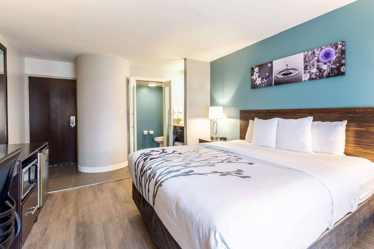 A hotel room with a large bed, a desk, and a bathroom visible through an open door.