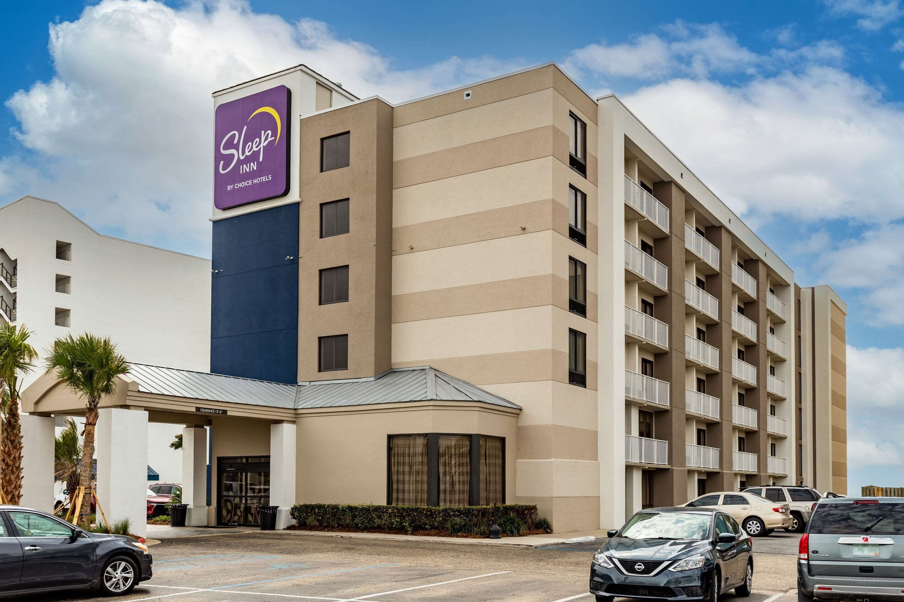 A Sleep Inn by Choice Hotels building with a parking lot and several cars.