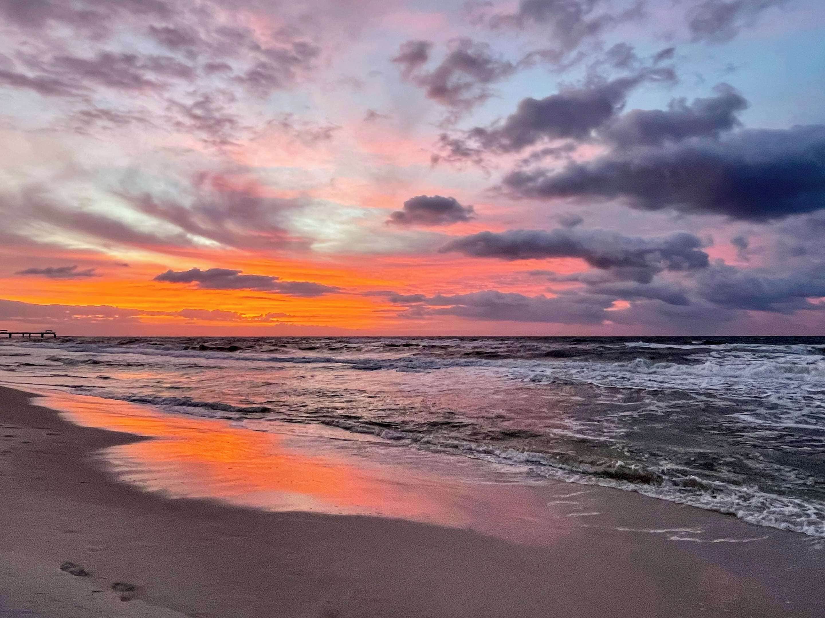 A beach with waves and a sunset.