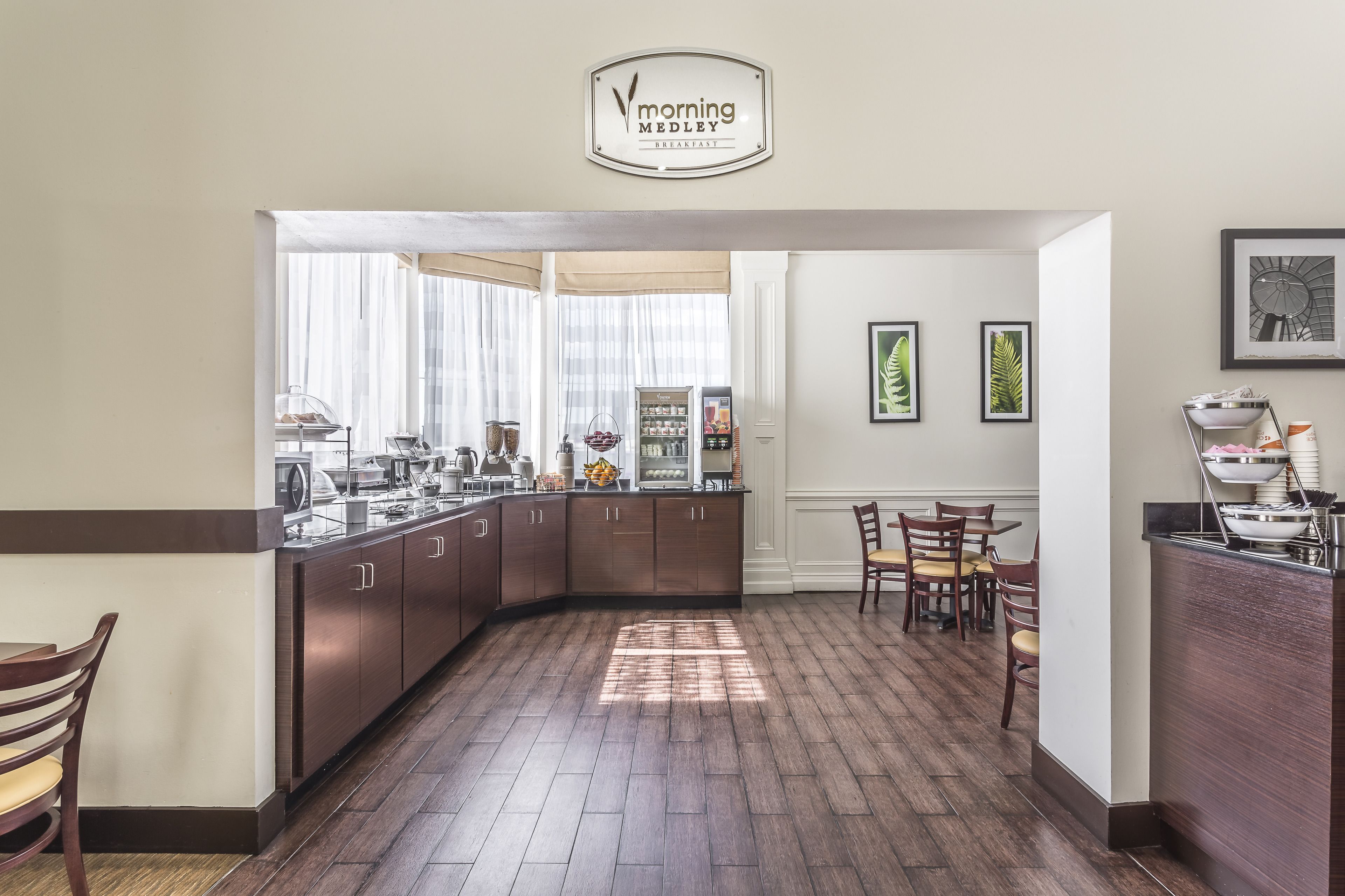 A modern kitchen with a breakfast bar, wooden cabinets, and a sign reading "Morning Medley Breakfast."
