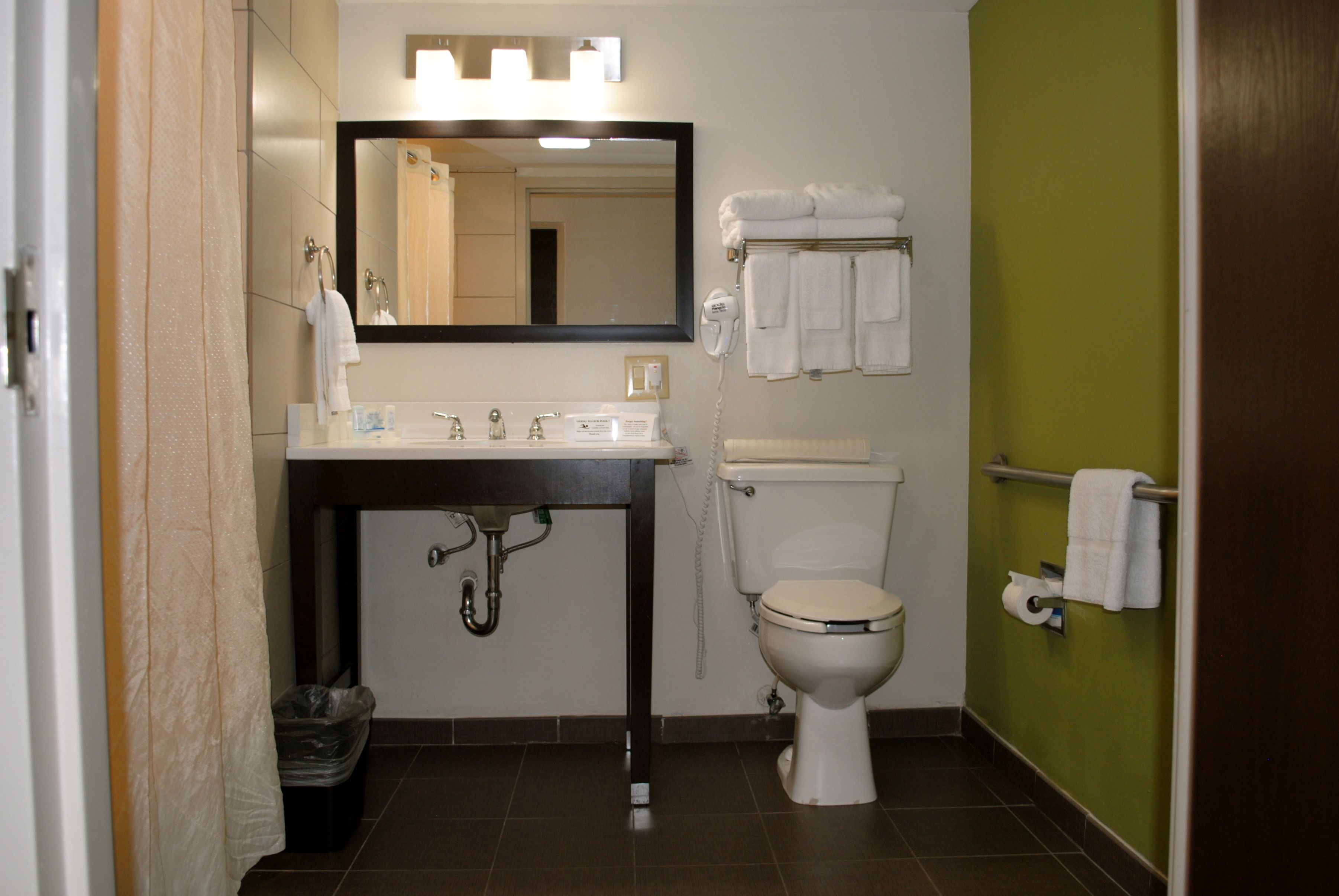 A bathroom with a sink, mirror, toilet, and towel rack.