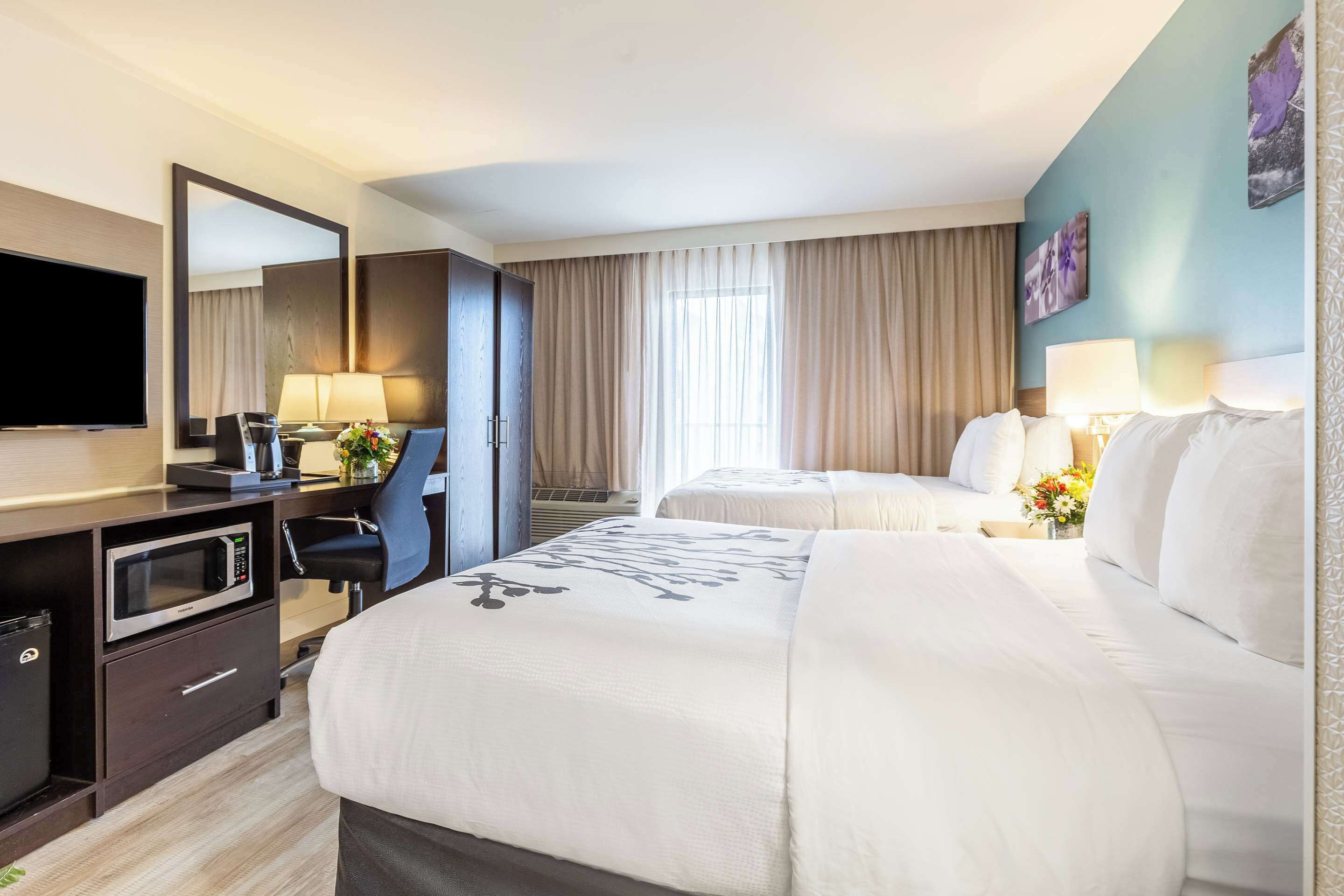 Een hotelkamer met een groot bed, een bureau met een computer, een televisie en een magnetron.