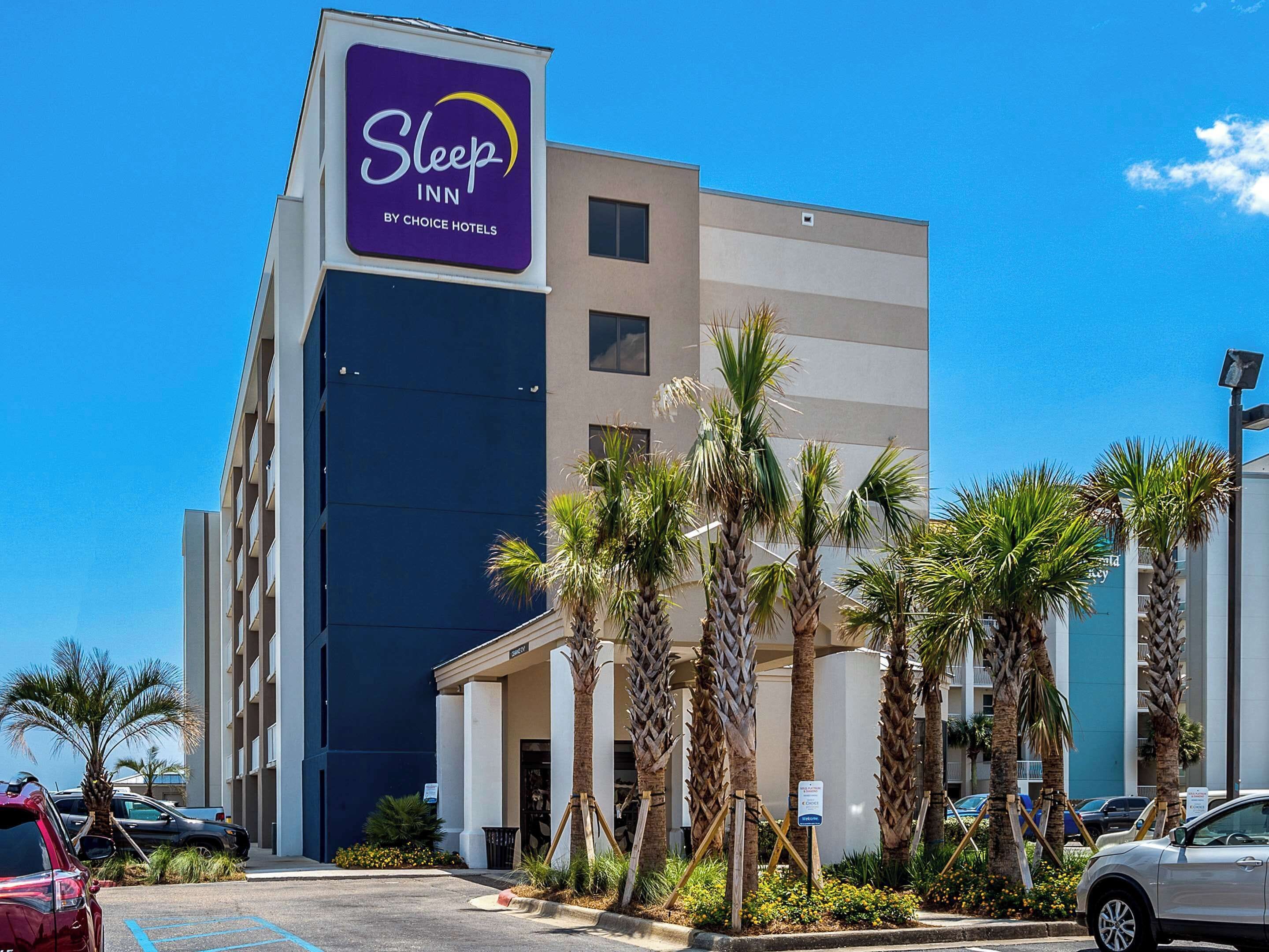 Edificio de Sleep Inn by Choice Hotels con diseño moderno, palmeras y estacionamiento.