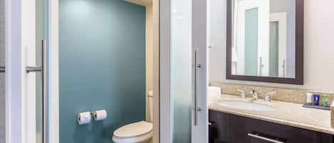 A bathroom with a toilet, sink, and mirror.