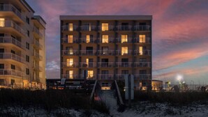 A multi-story hotel with balconies, a beachside location, and a staircase leading to the entrance.