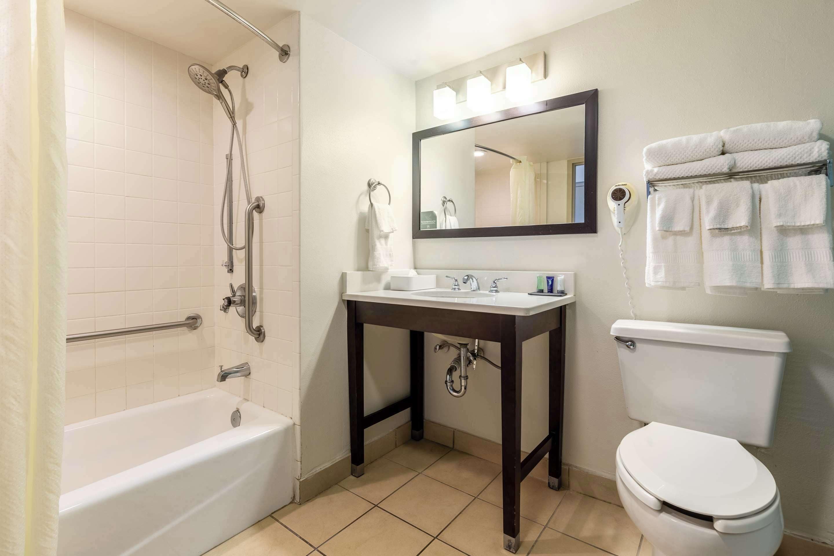 A bathroom with a bathtub, sink, mirror, and toilet.