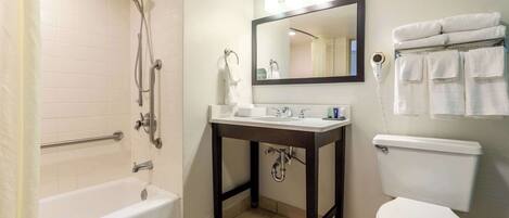 A bathroom with a bathtub, sink, mirror, and toilet.