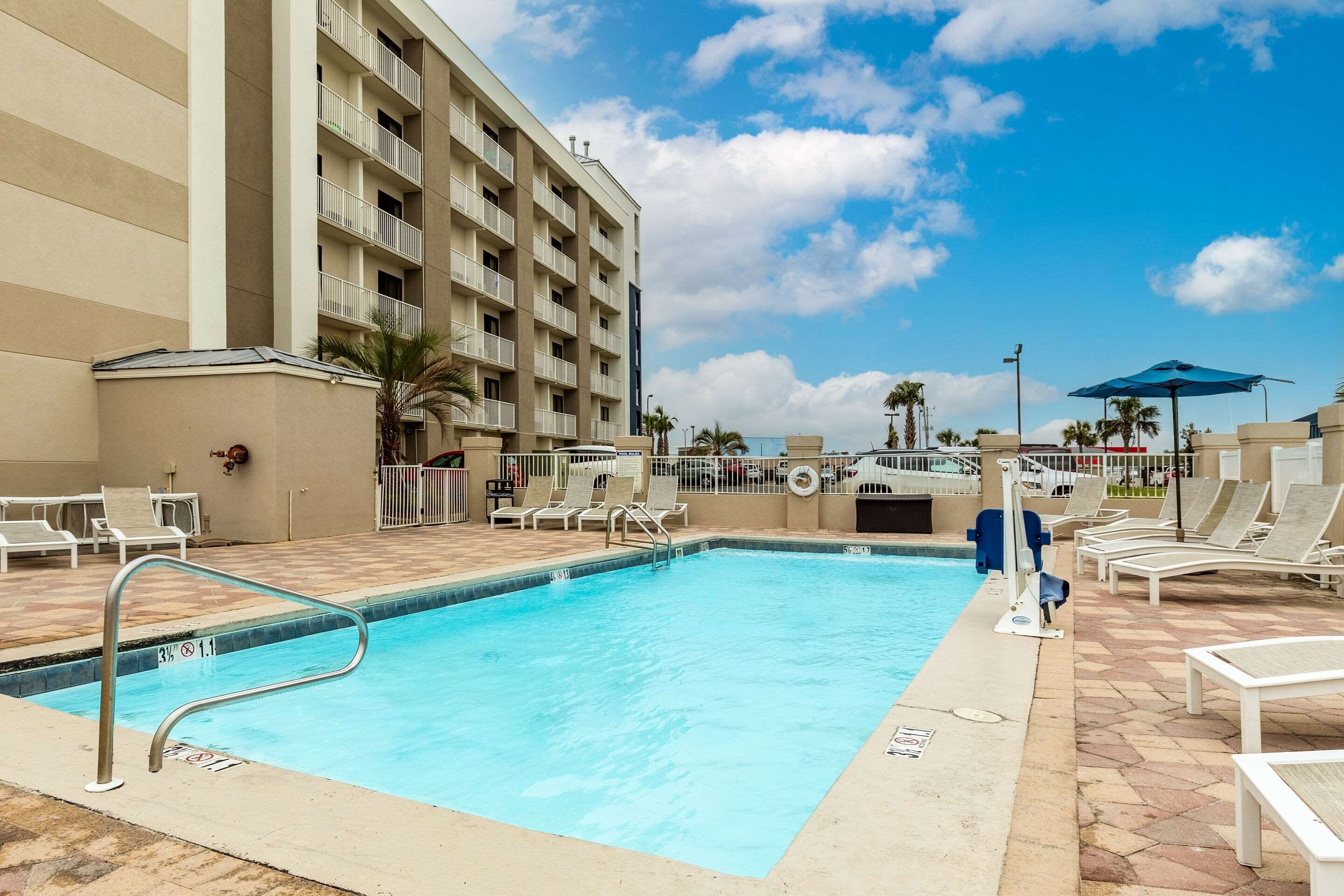 A swimming pool with lounge chairs and a building in the background.