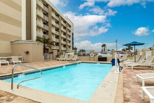 A swimming pool with lounge chairs and a building in the background.