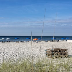 Relax on the beach with comfortable lounge chairs and umbrellas, surrounded by a well-maintained shoreline.