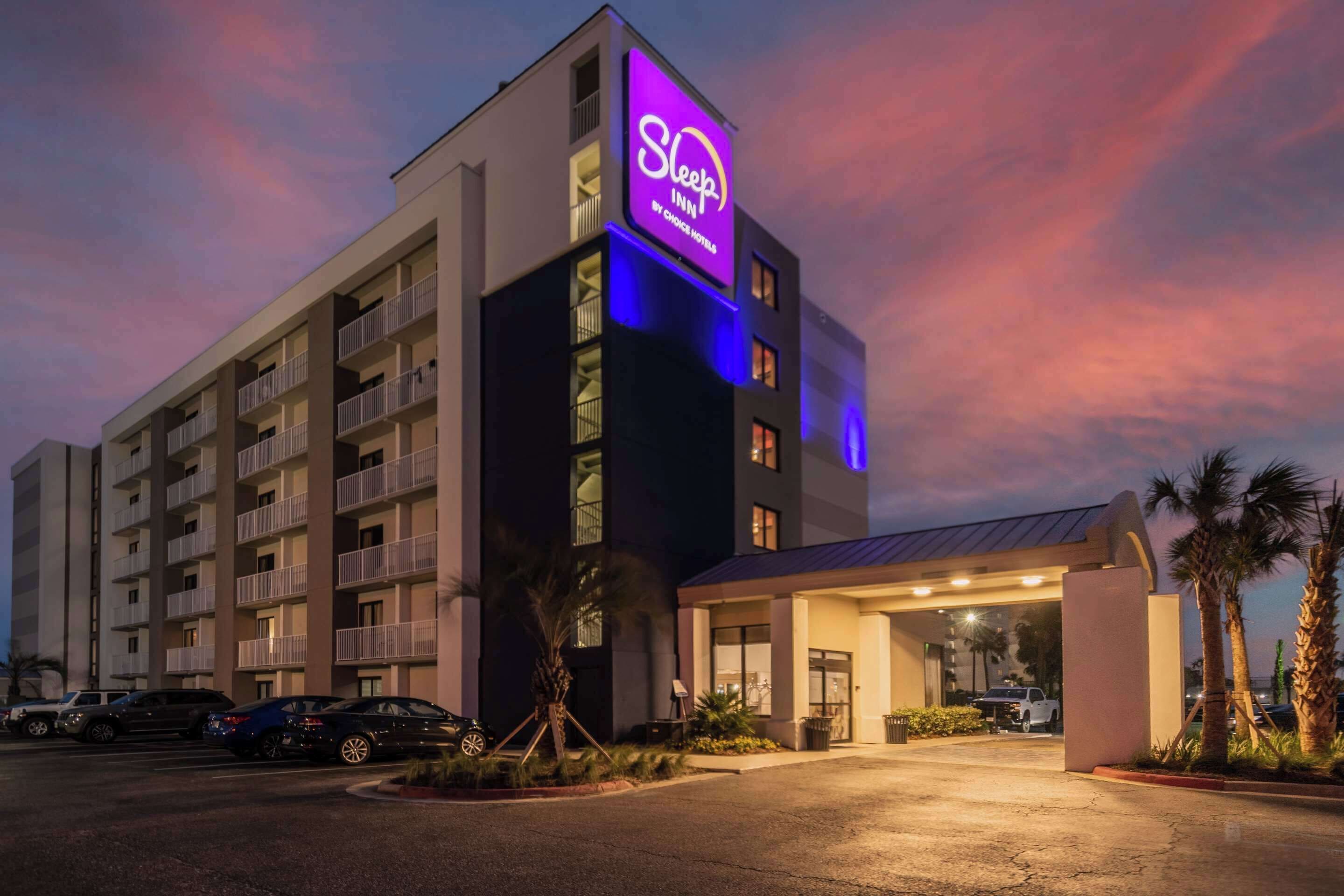 A Sleep Inn hotel with a prominent neon sign, multiple balconies, and a well-lit entrance.