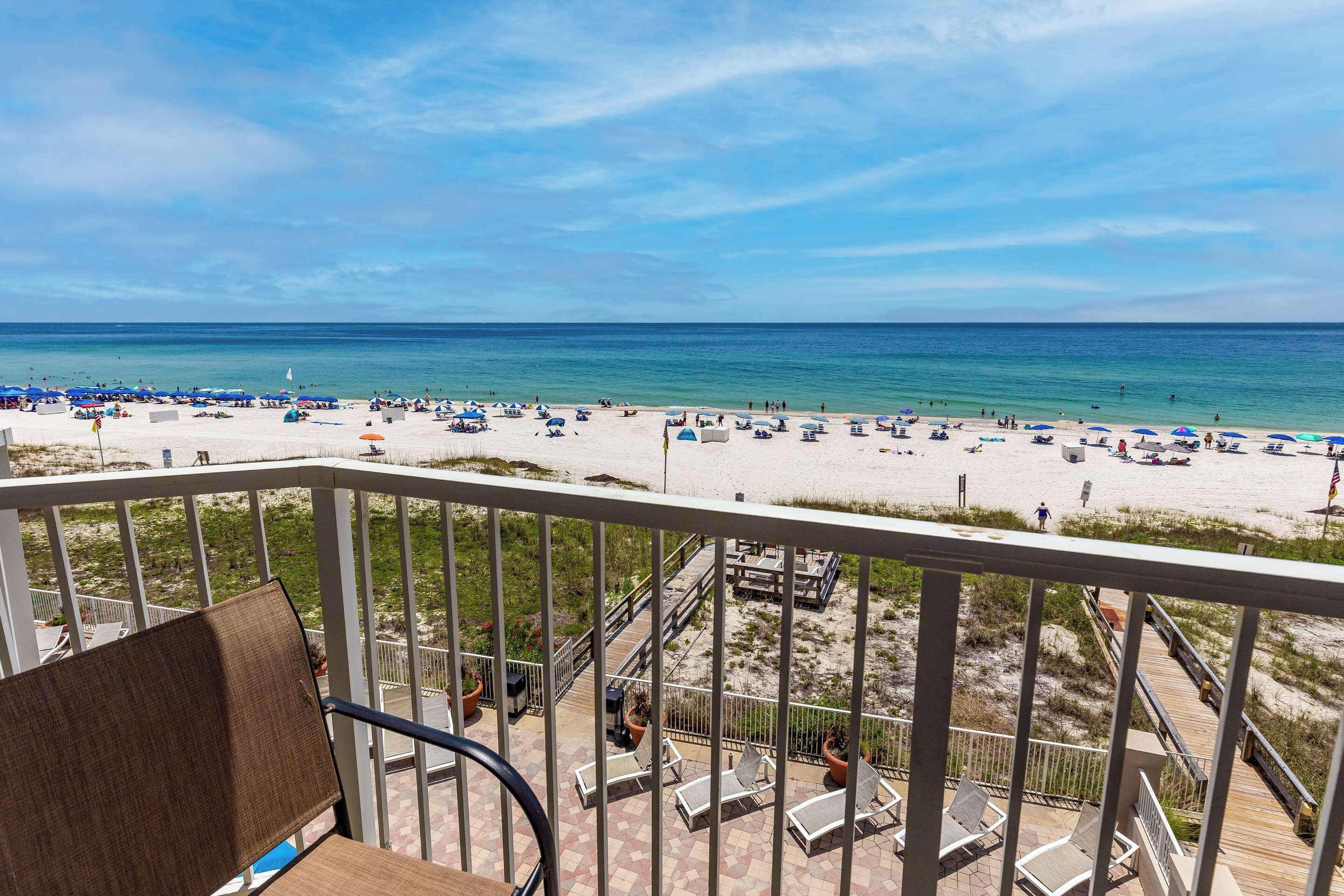 Uma varanda com vista para uma praia, com guarda-sóis e espreguiçadeiras.