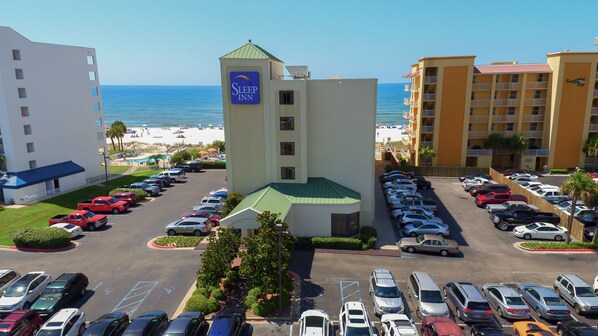 A hotel with a pool, a parking lot, and a view of the beach.