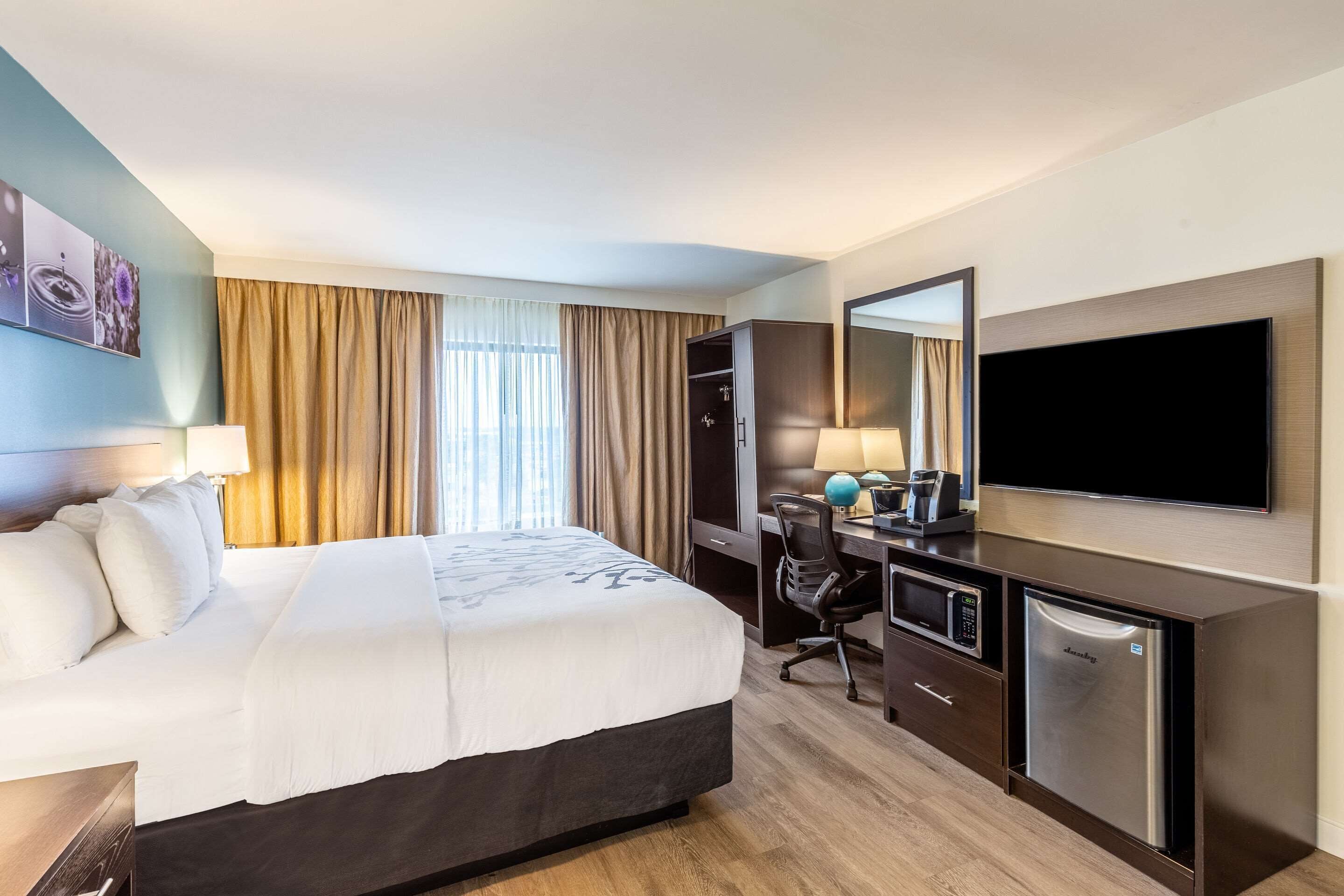 A hotel room with a bed, desk, and TV.