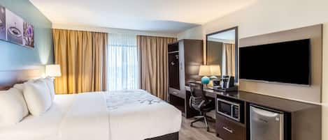 A hotel room with a bed, desk, and TV.