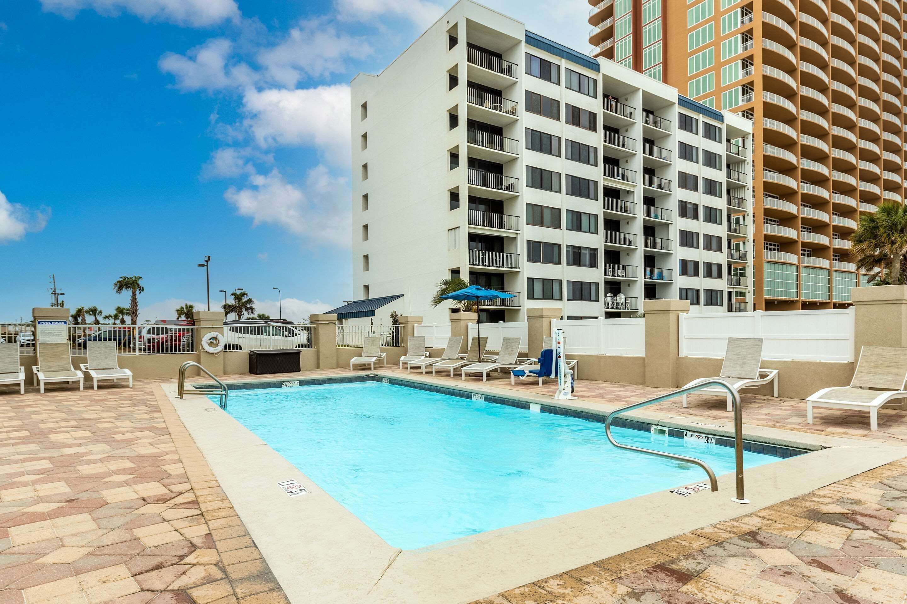 A swimming pool with lounge chairs and a tall building in the background.