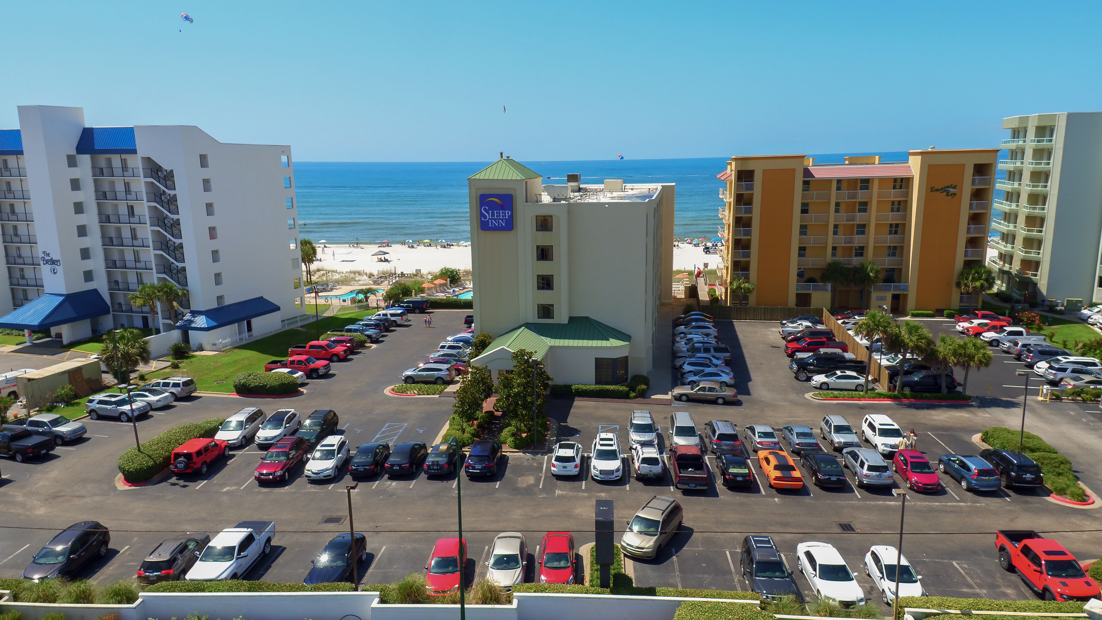 A hotel with a parking lot, a beach view, and a sign for 'Sleep Inn'.