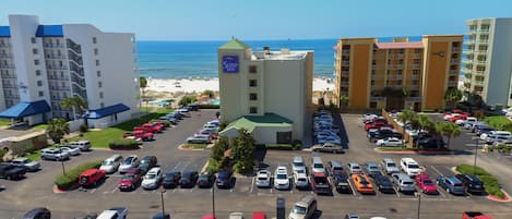 A hotel with a parking lot, a beach view, and a sign for 'Sleep Inn'.