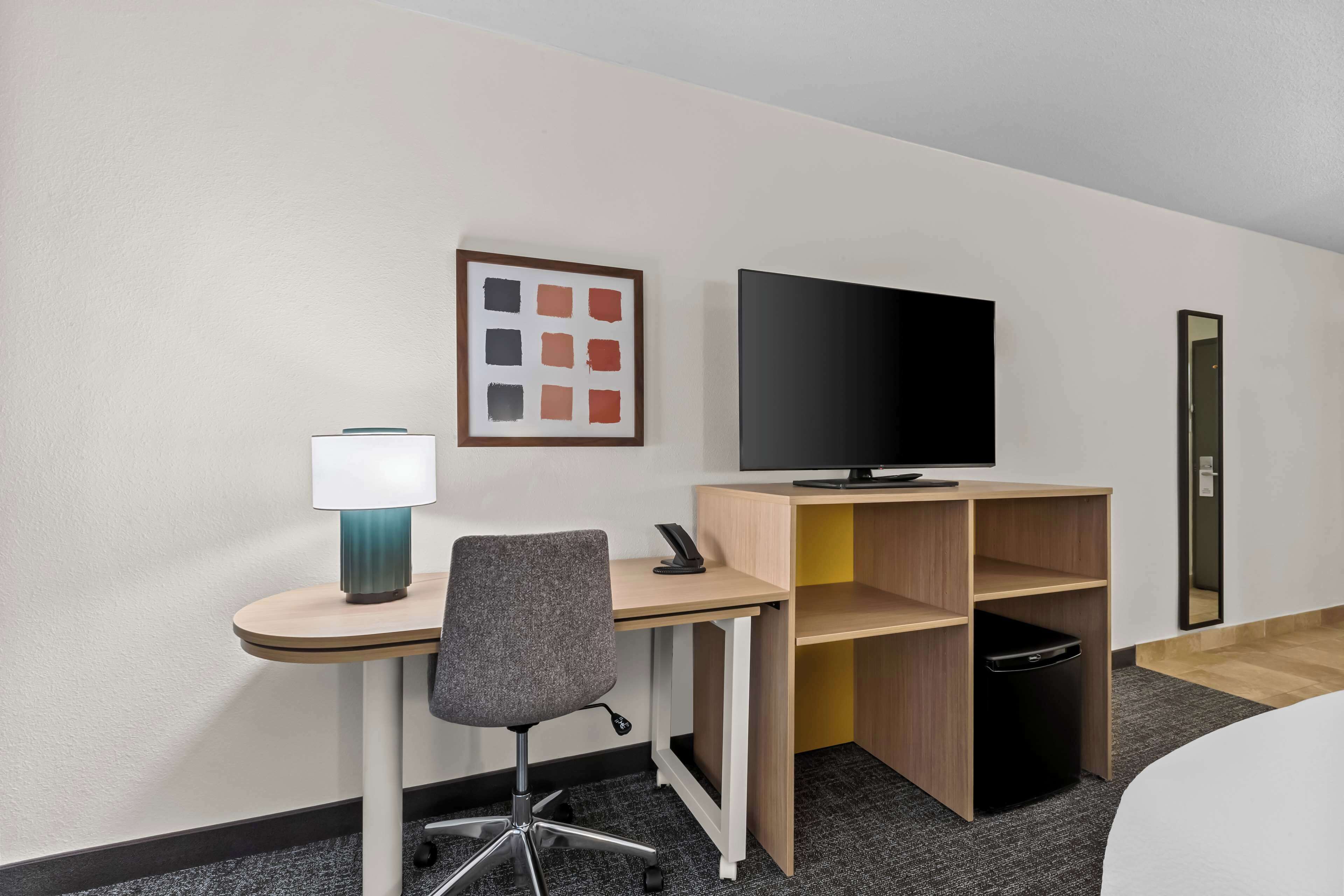 Une chambre d’hôtel équipée d’un bureau, d’une chaise, d’une télévision, d’une lampe et d’une petite poubelle.