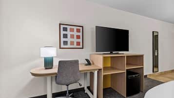 Une chambre d’hôtel équipée d’un bureau, d’une chaise, d’une télévision, d’une lampe et d’une petite poubelle.