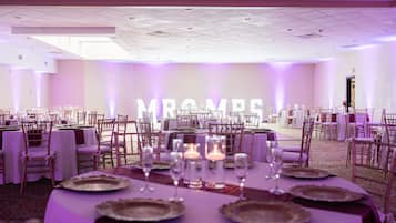A banquet hall with tables set for a formal event, featuring a large illuminated sign reading "MRS."