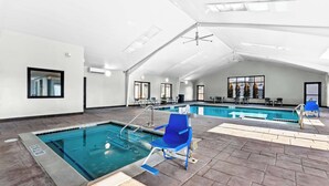 Uma piscina interior com trampolim, espreguiçadeiras e chão em mosaico.