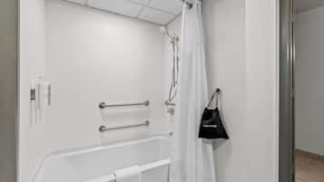 Um banheiro com uma banheira branca, chuveiro com cortina branca e uma bolsa de mão preta pendurada na parede.