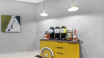 A modern bar area with a yellow counter, three coffee dispensers, and a wheelchair-accessible design.