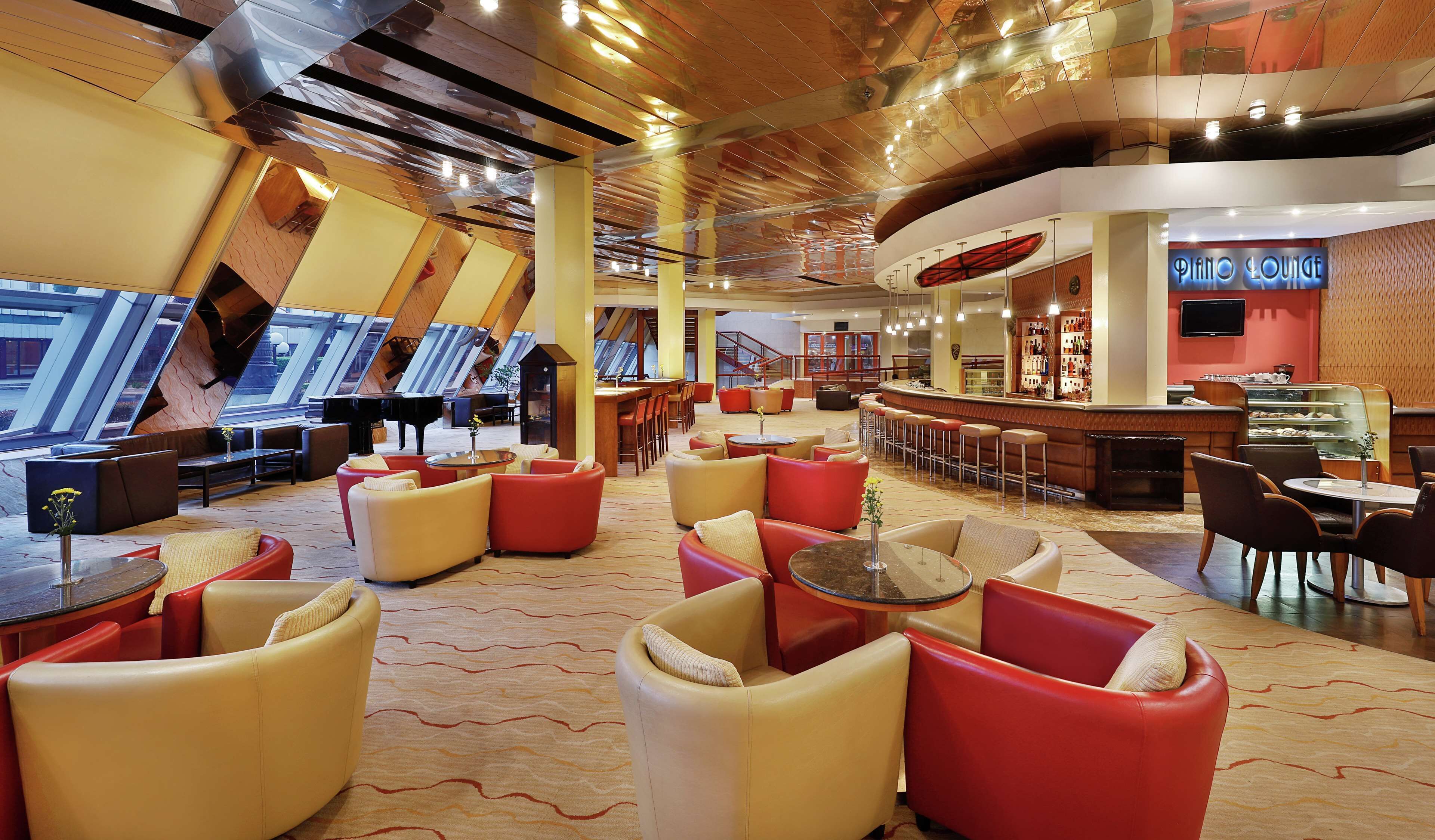 A spacious lounge area with multiple seating options, a piano, and a bar.