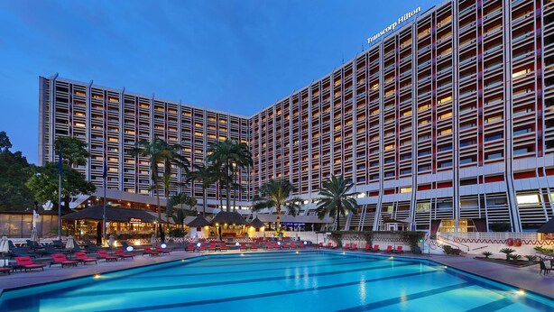 A hotel with a large pool, multiple floors, and outdoor seating areas. - Transcorp Hilton Abuja (Abuja)