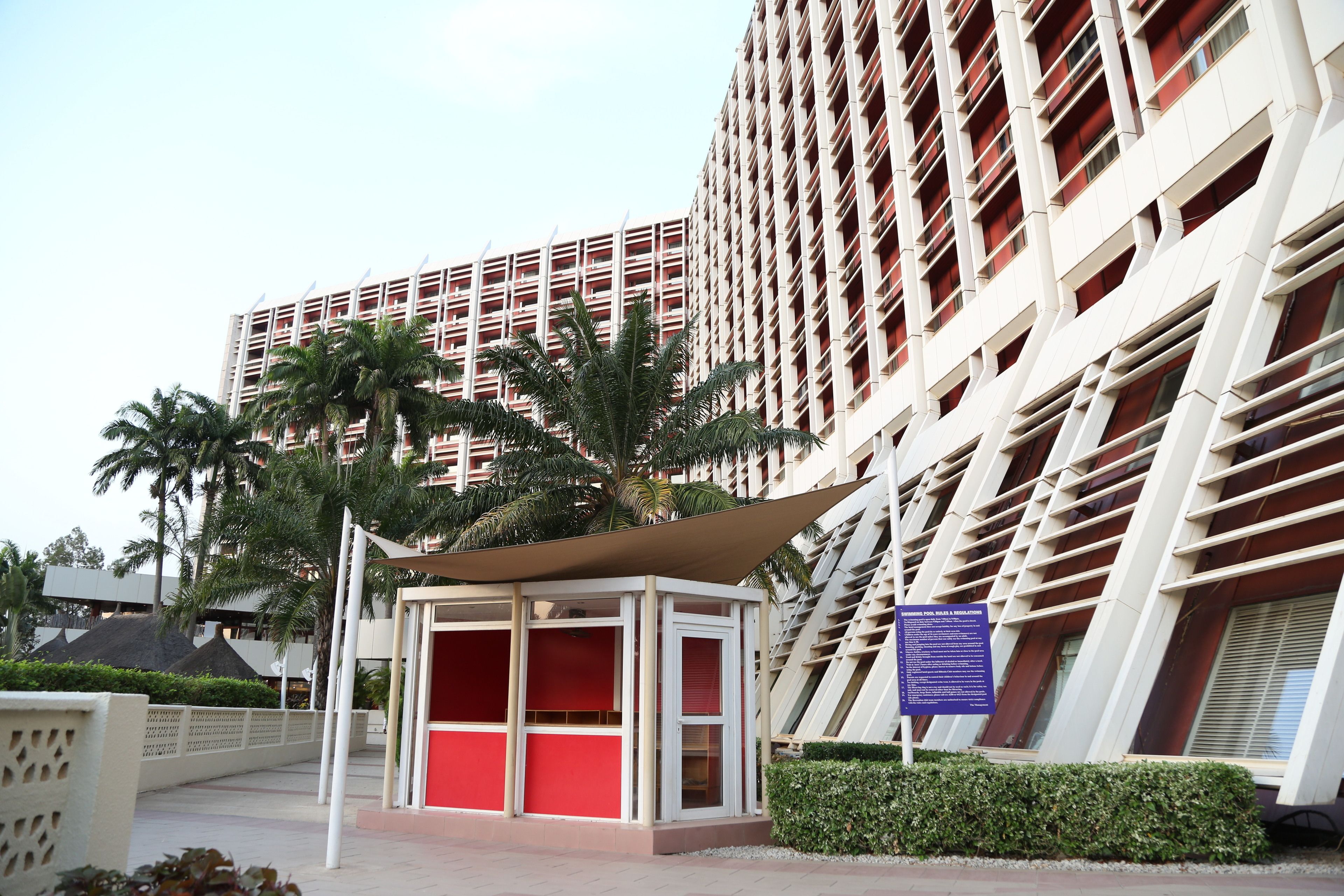 A modern building with a distinctive red and white facade, featuring a central red structure with glass panels and a surrounding white exterior.